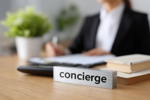 Woman Filling Out Document at Desk with Concierge Nameplate
