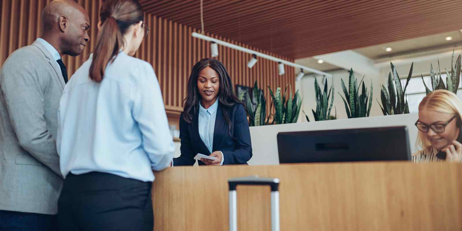 Concierge Team Checking in Two Smiling Hotel Guests