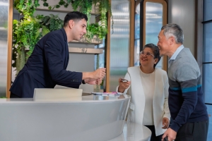 Friendly Concierge Assisting Senior Couple at Modern Residential Building Reception Desk