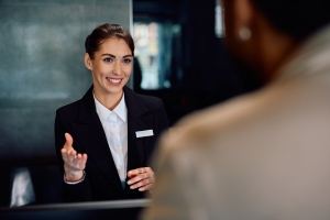 Smiling Receptionist Talking to Guest at Her Desk in Residential Building