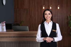 Smiling Female Concierge with Local Area Expertise Standing Near Her Desk
