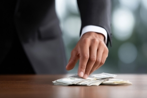 Property Manager Putting Hand on His Compensation Money on Table