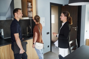 Smiling Female Property Manager Showing House to Young Couple