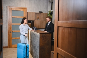 Apartment Concierge Assisting a Female Guest Checking in with Luggage