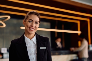 Happy Female Concierge Standing in Front of Her Desk in an Apartment Building