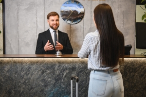 Male Concierge Talking Female Guest at Reception Desk